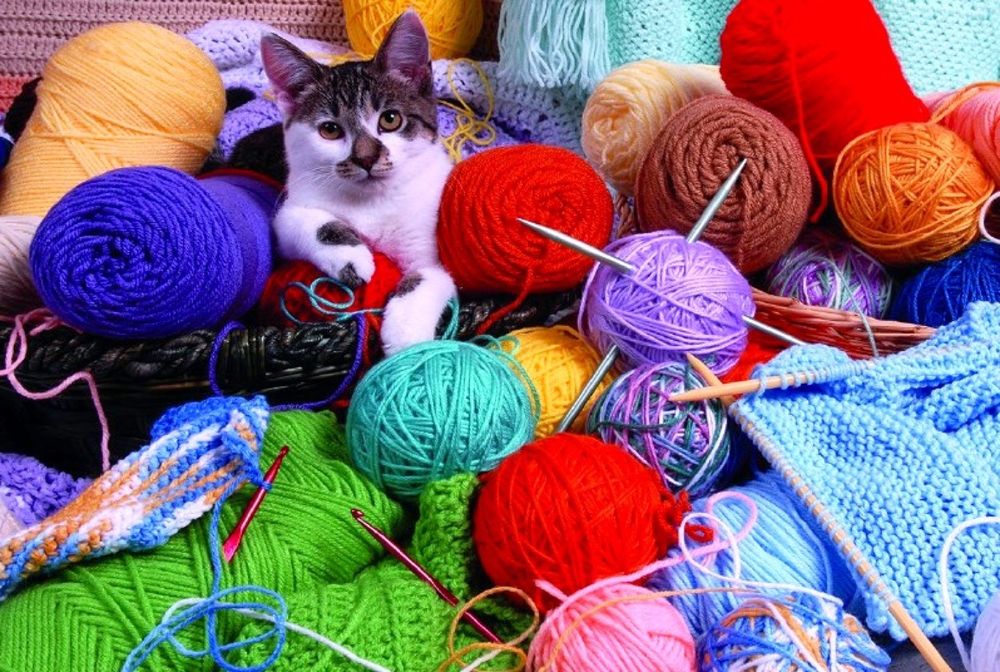Обои для рабочего стола Серо-белый котенок лежит на мотках разноцветной пряжи