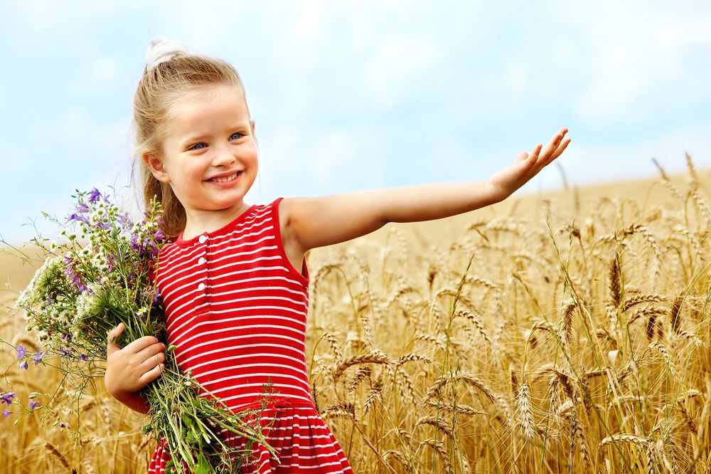 Обои для рабочего стола Девочка с букетом в руках стоит в пшеничном поле