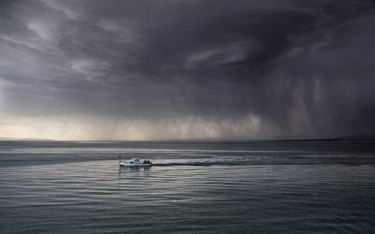 Обои на рабочий стол Катер в море, уходящий от надвигающейся грозы, в небе зловещая воронка