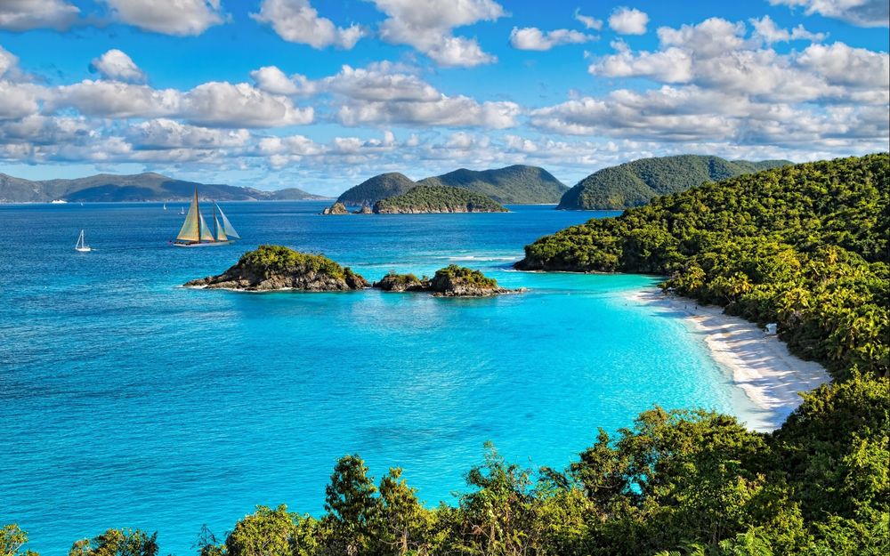 Обои для рабочего стола Virgin Islands, Trunk Bay / Национальный парк Виргинские острова, поросший деревьями берег, небо с пушистыми облаками, лазурное море и парусные яхты вдали