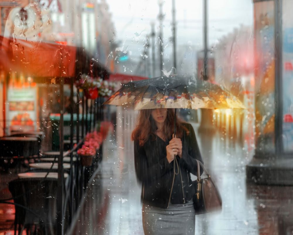 Обои для рабочего стола Девушка под зонтом идет в дождь по городской улице, фотограф Эдуард Гордеев