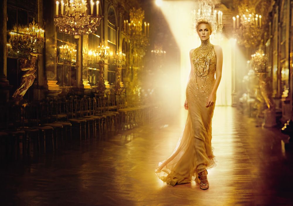 Обои для рабочего стола Актриса Charlize Theron / Шарлиз Терон в длинном платье идет по богато убранному залу в солнечных лучах, в рекламе духов JAdore от Dior