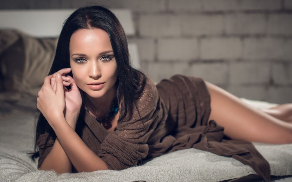 Обои для рабочего стола Модель Angelina Petrova / Ангелина Петрова смотрит на нас, лежа в платье на кровати