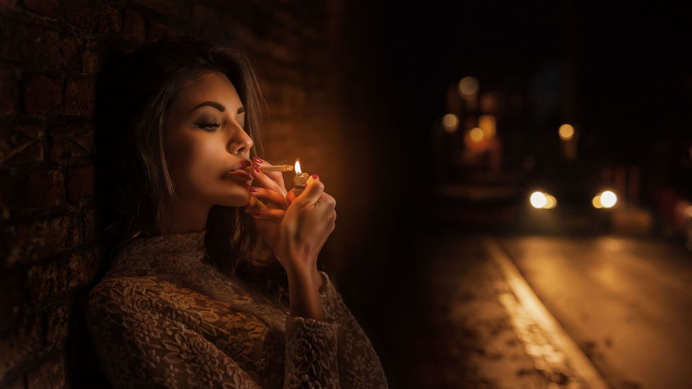 Обои для рабочего стола Девушка сидит у дороги и прикуривает сигарету, фотограф Tonny Jоrgensen