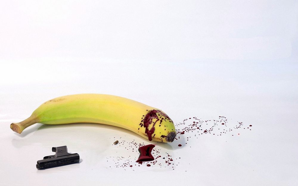 Обои для рабочего стола Застрелившийся банан с каплями крови и лежащим рядом пистолетом Marius S
