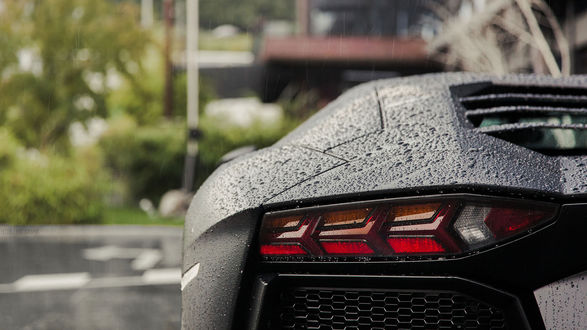 Обои на рабочий стол Подфарники черного Lamborgini, стоящего на парковке у дома