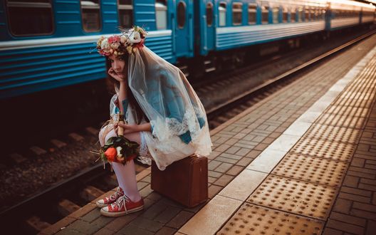 Обои на рабочий стол Девушка с букетом цветов, в кроссовках и подвенечной фате, ожидая поезда, сидит на чемодане