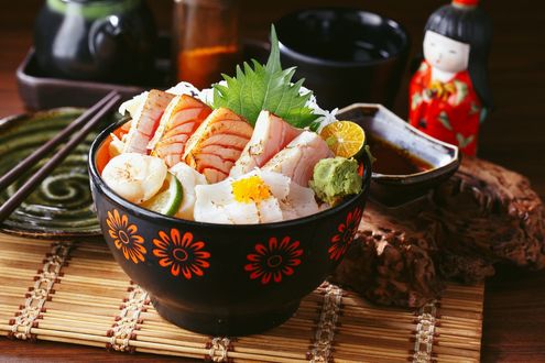 Обои на рабочий стол Японская кухня, кусочки рыбы с васаби в миске, стоящей на циновке, рядом соус и сувенирная кукла