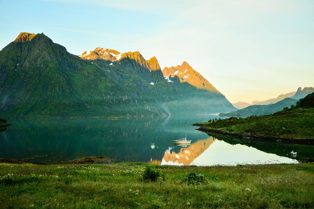 Обои для рабочего стола Vester&;len Lofoten in Norway / Лофотенские острова, Норвегия, водоем, катер, горы вершины которых подсвечены солнцем