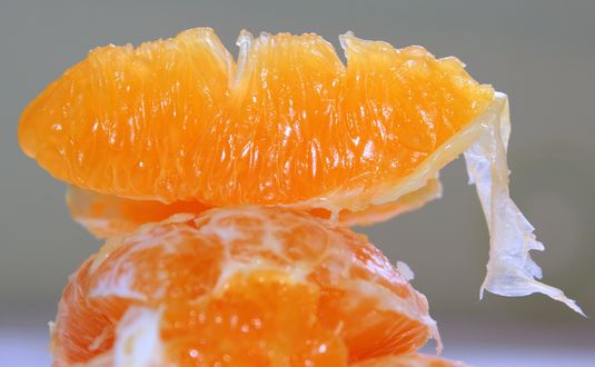 Обои на рабочий стол Очищенные дольки мандаринов, на сером фоне, в макросъемке
