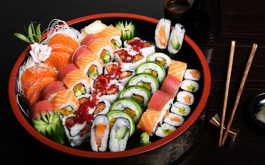 Обои на рабочий стол Японская кухня: различные роллы с красной рыбой и огурцом в круглой коробочке, рядом полочки для еды