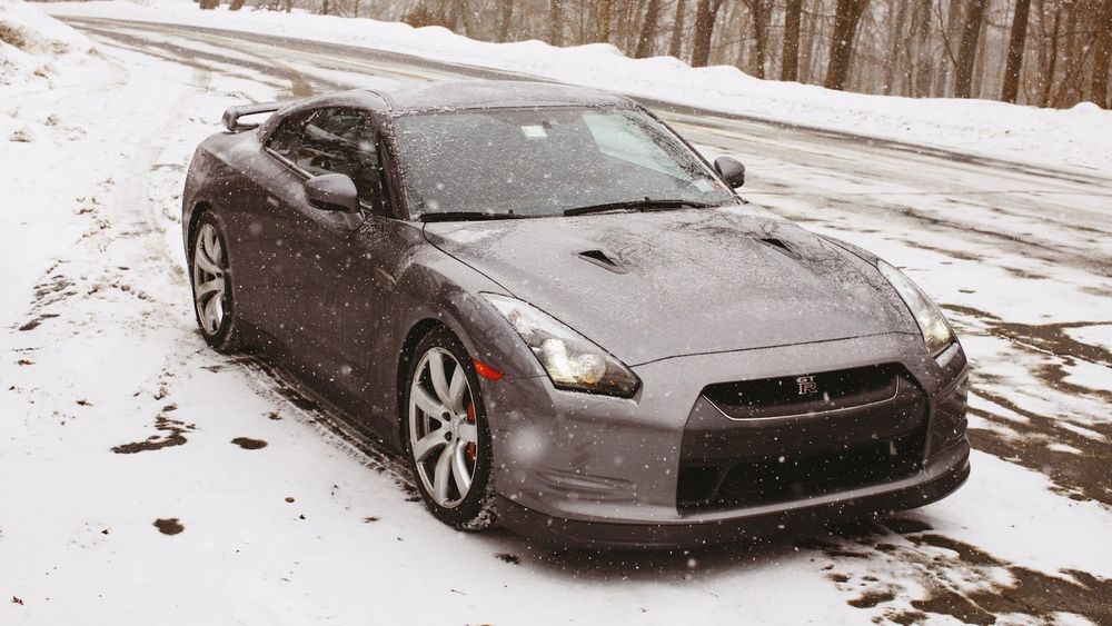 Обои для рабочего стола Nissan Gt-R стоит на дороге под падающим снегом