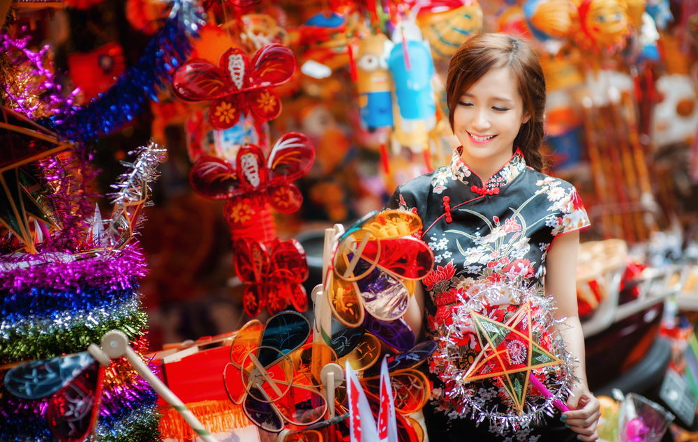 Обои для рабочего стола Улыбающаяся китаянка держит в руках игрушки, стоя в сувенирной лавке
