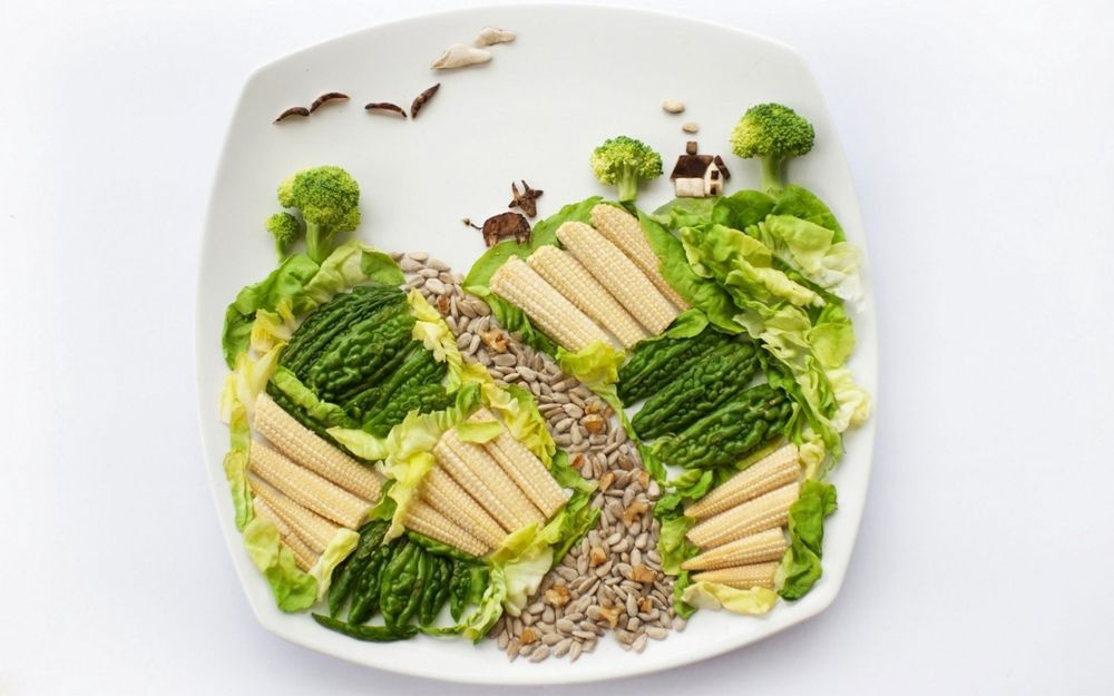 Обои для рабочего стола Кукуруза, салат, семечки, брокколи и зеленый перец разложены на тарелке в виде сельского пейзажа