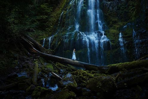 Обои на рабочий стол Девушка в длинном платье стоит на фоне водопада, by TJ Drysdale