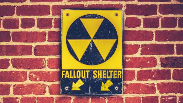 Обои на рабочий стол Знак радиационной опасности с надписью Fallout shelter на фоне кирпичной стены