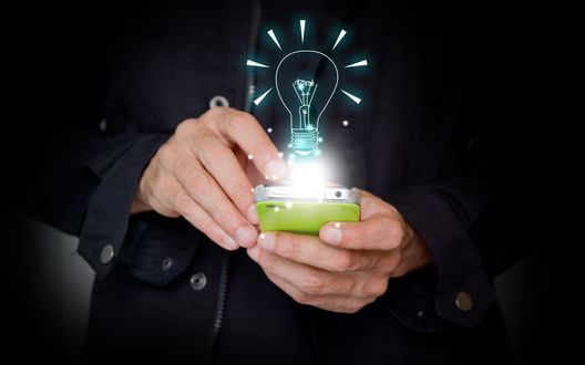 Обои на рабочий стол Мужчина со смартфоном в руках и над смартфоном есть свечение и нарисованная лампочка