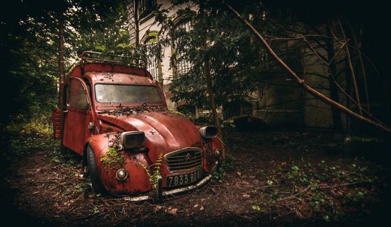 Обои на рабочий стол Старая машина марки citroen стоит в леске у здания