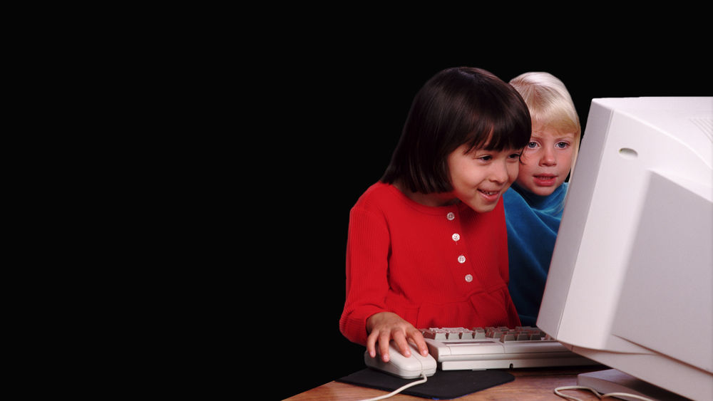 Обои для рабочего стола Две маленькие девочки сидящие у компьютера на черном фоне