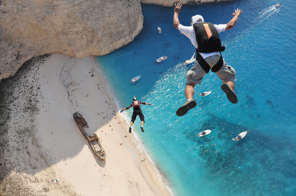 Обои для рабочего стола Бухта Навайо / Navagio Beach / Навагио (Закинф), парень прыгает со скалы с парашютом