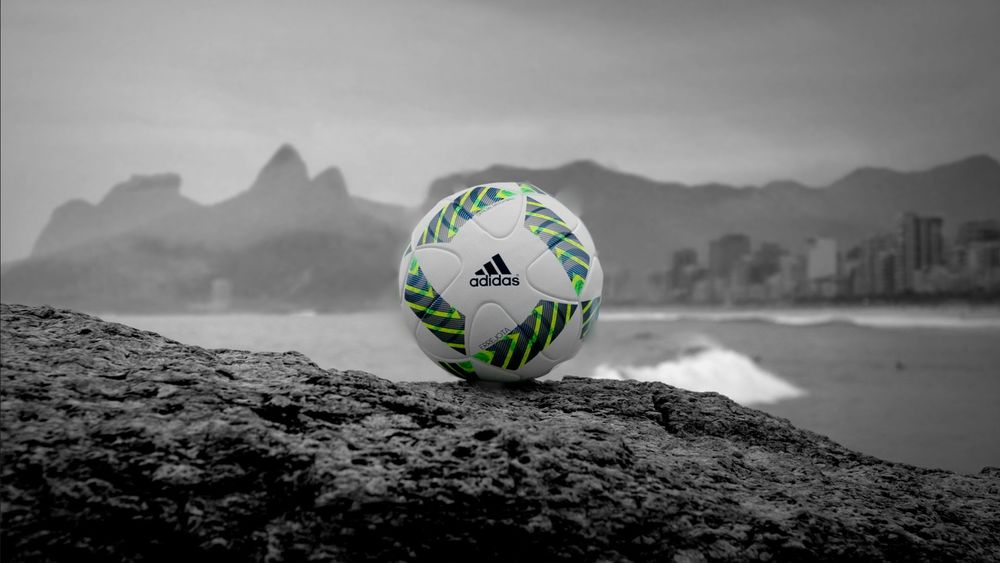Обои для рабочего стола Белый мяч фирмы Adidas на фоне гор, пляжа и города
