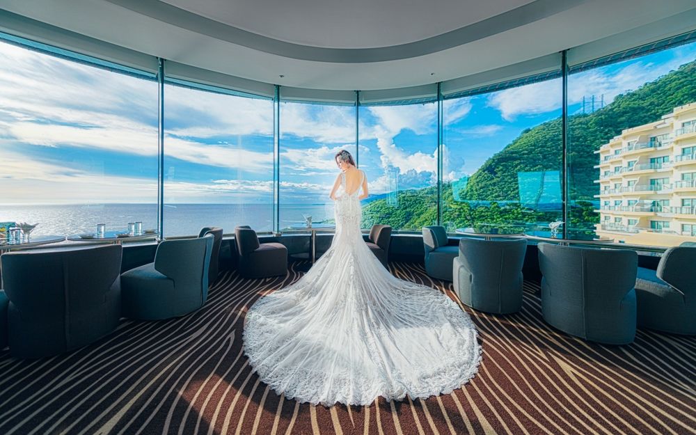 Обои для рабочего стола Девушка в белом, длинном платье стоит в одной из комнат гостиницы у окна с видом на море