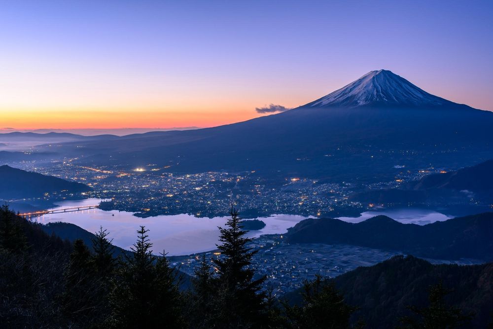 Обои для рабочего стола Japan / Япония, священная гора Fuji / Фудзияма, вечер, сияет огнями город у ее подножия