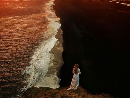 Обои на рабочий стол Девушка в длинном платье стоит у моря, фотограф TJ Drysdale