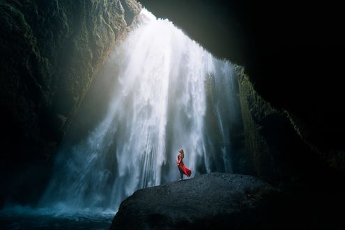 Обои на рабочий стол Девушка в красном платье стоит на фоне водопада, фотограф Lizzy Gadd