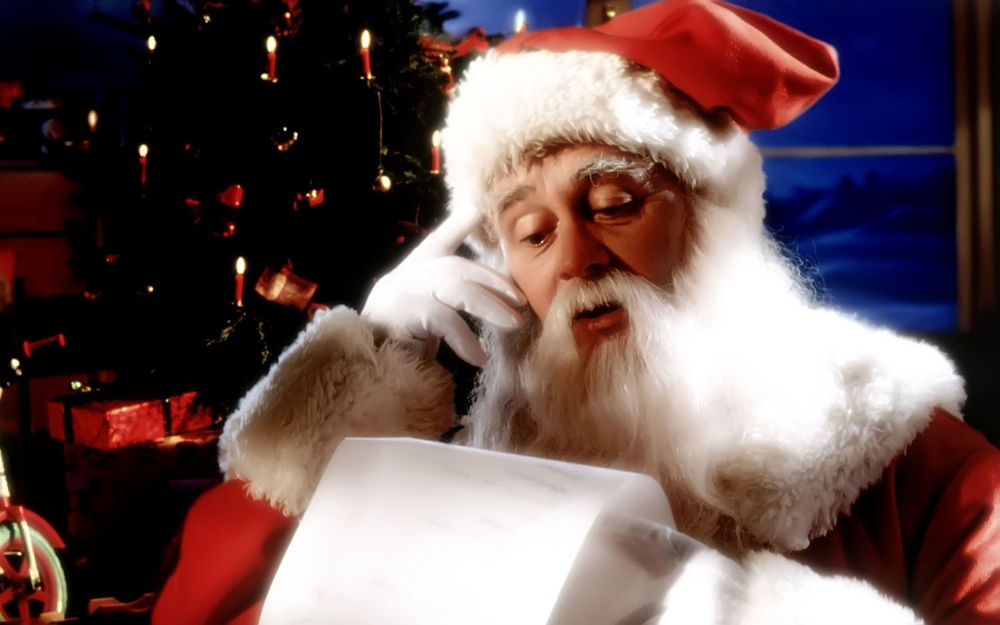 Обои для рабочего стола Санта Клаус читает письмо возле елки