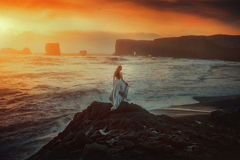 Обои на рабочий стол Девушка в длинном платье стоит на фоне моря, фотограф TJ Drysdale