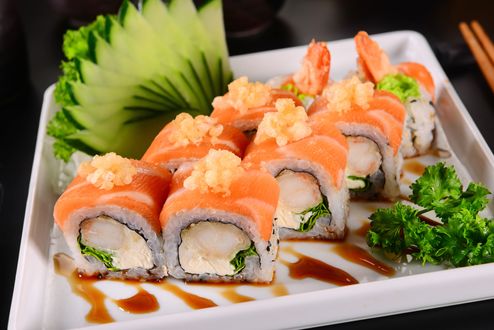 Обои на рабочий стол Японская кухня: роллы с красной рыбой, зеленью и огурцом в белой коробочке, рядом полочки для еды