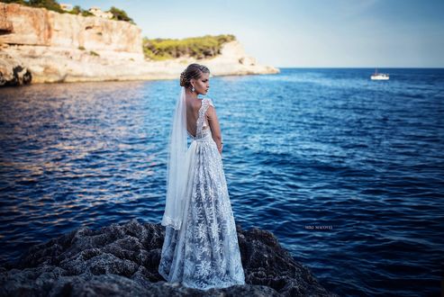 Обои на рабочий стол Девушка в длинном платье стоит на фоне моря, фотограф Miki Macovei