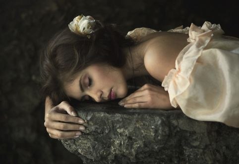 Обои на рабочий стол Девушка с цветком в волосах лежит на камне, фотограф Magdalena Russocka