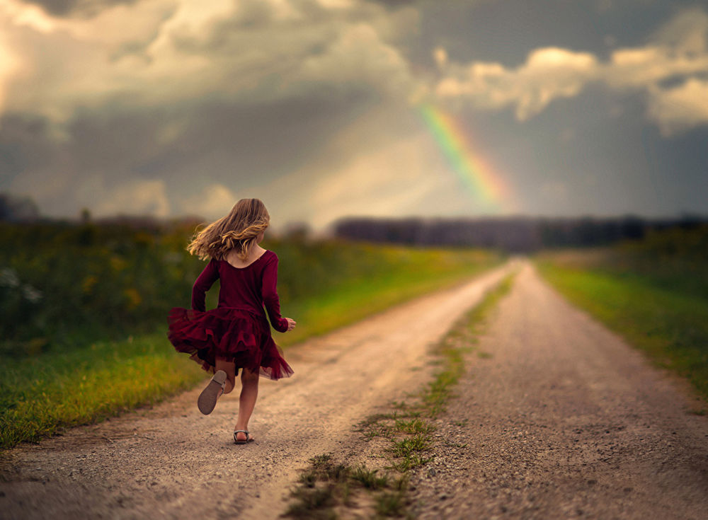 Обои для рабочего стола Маленькая девчушка бежит по дороге навстречу радуге, стараясь не отпустить свое счастье