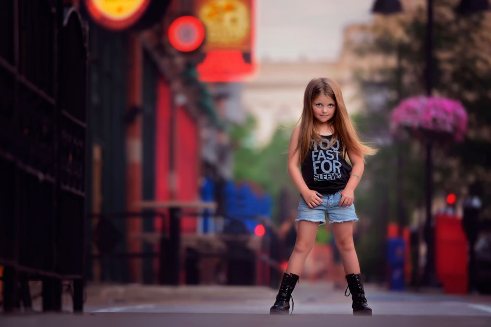 Обои для рабочего стола Девочка, в голубых шортах, черных майке и ботинках, стоит на улице города, расставив ноги
