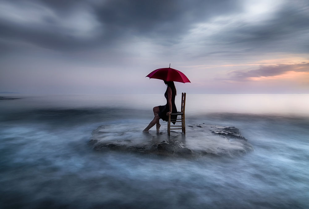 Обои для рабочего стола Девушка с красным зонтом сидит на стуле на фоне облаков, by justeline