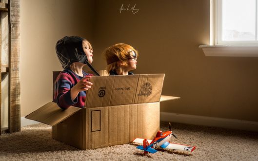 Обои на рабочий стол Дети сидят в коробке, играя в летчиков, фотограф Adrian C. Murray