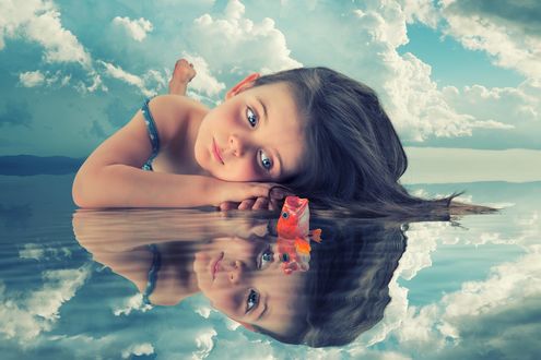 Обои на рабочий стол Девочка лежит на воде перед рыбкой, фотограф John Wilhelm