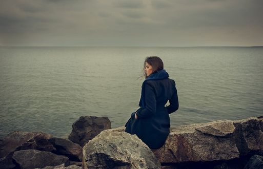Обои на рабочий стол Девушка в пальто сидит на камнях у моря, фотограф Valeriya Tikhonova