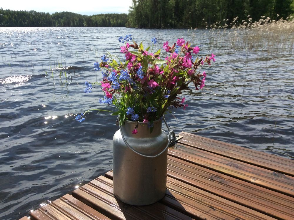 Обои для рабочего стола На мостках лесного озера стоит бидон с полевыми цветами