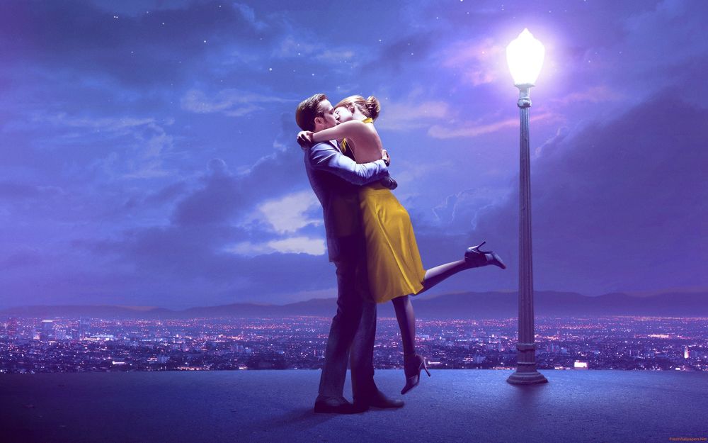 Обои для рабочего стола Влюбленные обнимаются и целуются на крыше здания под фонарем, на фоне города и ночного неба