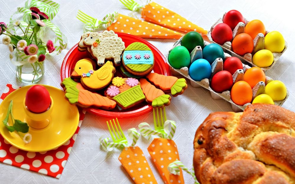 Обои для рабочего стола На праздник Пасхи накрыт стол с разными сладостями, крашенными яйцами и куличом и цветами в банке