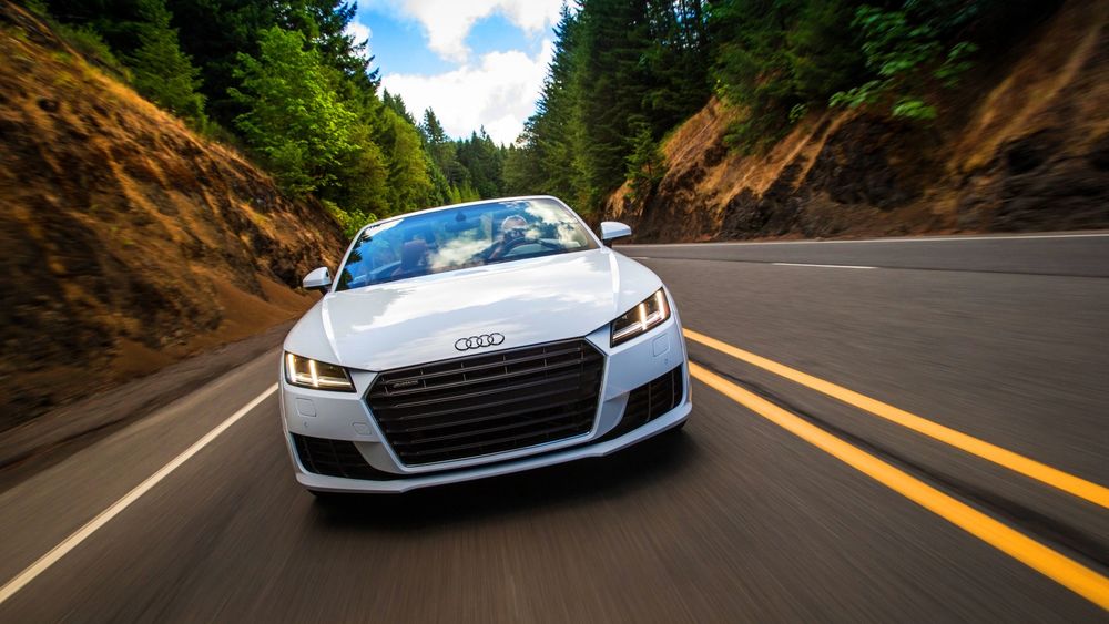 Обои для рабочего стола Автомобиль Audi TT Roadster мчится по дороге в лесу