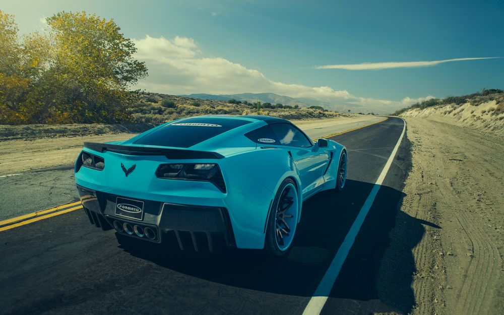 Обои для рабочего стола Голубой Chevrolet Corvette C7 Stingray, тюнингованный фирмой Forgiato, стоит на свежевыложенном асфальте в горной местности