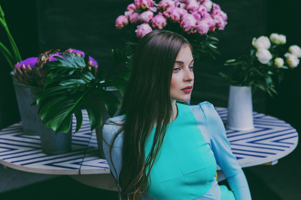 Обои для рабочего стола Модель Anna Raise / Анна Райз сидит у стола, где стоят цветы в вазах