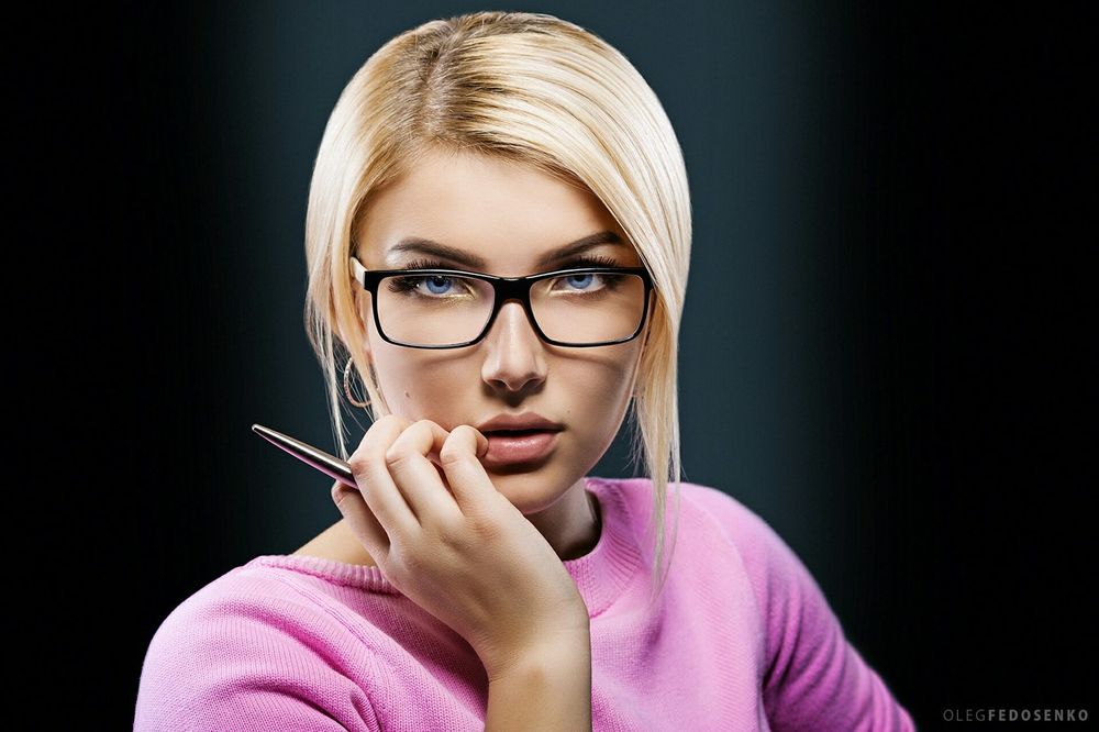 Обои для рабочего стола Модель Вика со светлыми волосами в очках держит ручку в руке на темном фоне. Фотограф Олег Федосенко