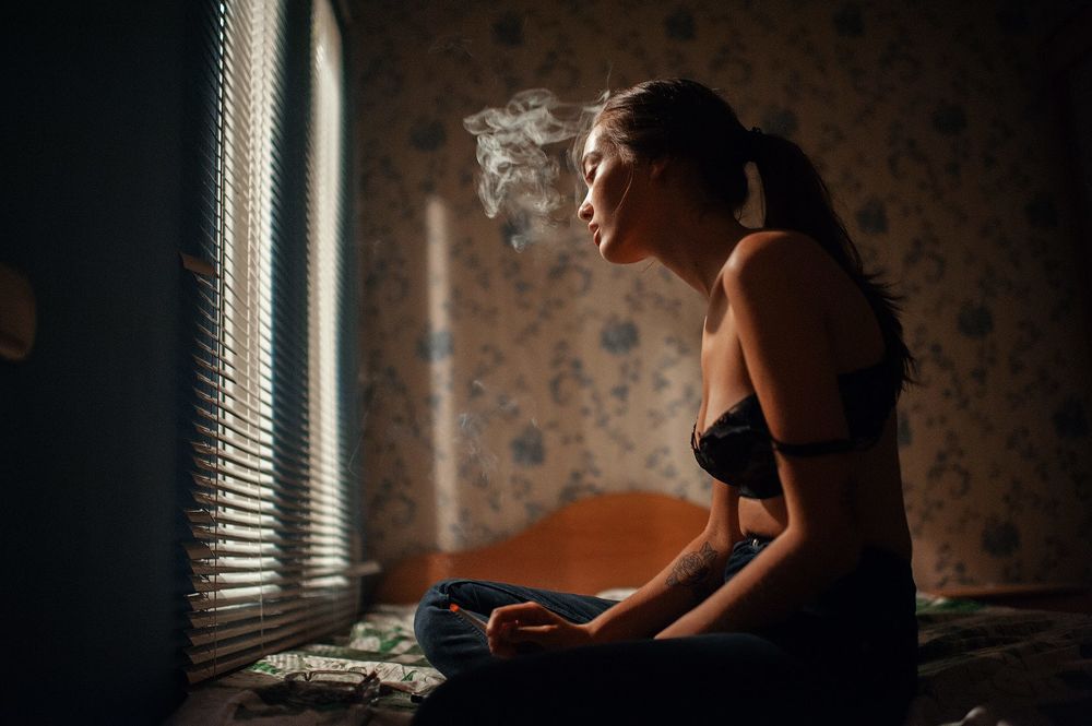 Обои для рабочего стола Девушка с сигаретой в руке сидит у окна, фотограф Marat Safin