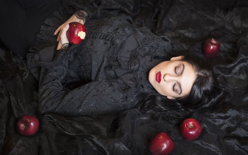 Обои для рабочего стола Девушка в черном лежит с закрытыми глазами, вокруг красные яблоки