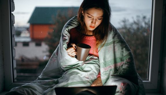 Обои на рабочий стол Девушка с чашкой в руке сидит перед ноутбуком, фотограф Marat Safin